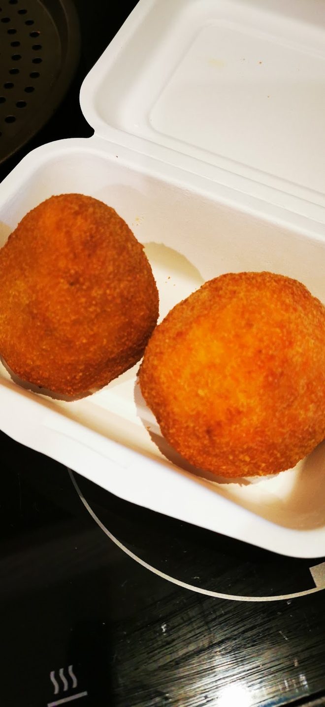 Fried arancini in a white takeaway box