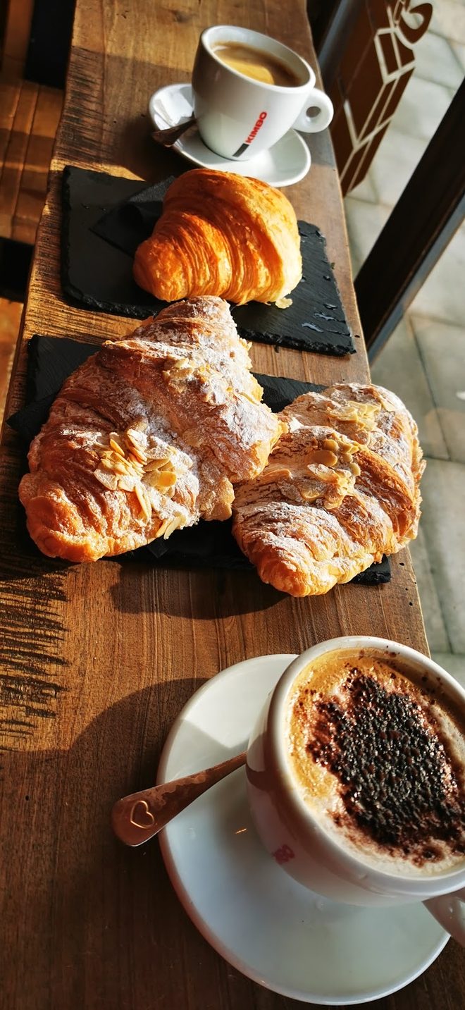 A cappuccino and espresso beside croissants